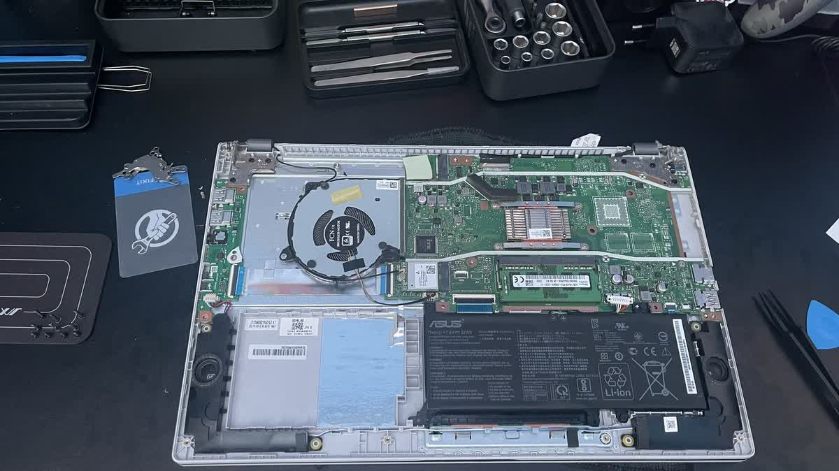 Szetszedett Asus laptop a szervizasztalon: litium akkumulator, alaplap, ventilator es szerszamok